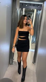 Vestido corto strapless de lurex negro, con diseño ajustado y aberturas laterales en la zona de la cintura.