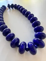 Collar de cuentas redondas y aplanadas con efecto marmolado en tonos grisáceos, con cierre metálico dorado.
