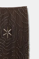 Pantalón de tiro alto, pierna recta y forro interior tipo shorts. Confeccionado en tejido negro con bordado floral en lentejuelas y abalorios dorados.
