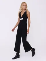 Mono largo negro con escote en V y detalle de lazo blanco en la cintura.