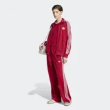 Pantalón deportivo Adidas Firebird Pinstripe color rojo con finas rayas verticales y las clásicas tres tiras blancas en los laterales. Cuenta con tiro medio, bolsillos laterales con cierre y el logo del trifolio bordado en blanco.