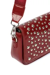 Bandolera pequeña de color rojo con solapa frontal decorada con tachas metálicas plateadas. Incluye una correa larga ajustable de tela al tono y herrajes metálicos.