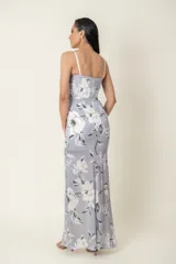 Vestido largo de fiesta color plateado con estampado floral blanco, escote corazón, breteles finos y falda cruzada con abertura lateral. Corsé con ballenas.