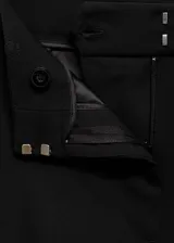 Pantalon de vestir negro de corte acampanado y tiro alto. Presenta trabillas para cinturón, bolsillos laterales y costuras decorativas frontales.