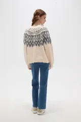 Cardigan de tejido jacquard con diseño geométrico en la parte superior, cuello redondo y cierre frontal con botones. Presenta un corte holgado y mangas largas con puños acanalados.