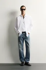 Camisa slim fit de Zara confeccionada en tejido de algodón con textura estructurada, cuello clásico con solapa y manga larga con puños abotonados. Cierre frontal con botonadura.