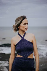 Vestido corto de punto con lurex color violeta, con cuello halter cruzado y aberturas en la cintura.
