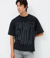 Remera masculina de corte boxy y calce amplio, color negro con estampa tipográfica "Guilt" en el frente. Cuenta con cuello redondo y mangas cortas.