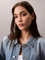 Campera de denim Calvin Klein en tono azul lavado, con corte relajado, cierre frontal con botones metálicos y doble bolsillo frontal con solapa.