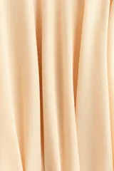 Pollera mini escalonada de punto de crepé color beige, con pretina ancha y cinturón para atar lateralmente en forma de lazo.