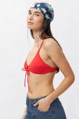 Top de bikini blanco con escote halter, abertura circular en el centro y lazos ajustables.