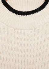 Jersey de punto acanalado en color crema, con cuello perkins y detalles de ribetes en contraste color negro en el cuello y el ruedo. Presenta un diseño recto de manga larga.