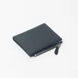Billetera de cuero sintético negro, de diseño compacto con cierre de cremallera en el compartimento principal.