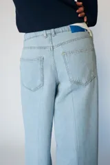Jeans de tiro medio con diseño wide leg y pernera ancha. Presenta cinco bolsillos, cierre frontal con cremallera y botón, y detalle de raya planchada en el delantero y la espalda.