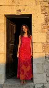 Vestido largo color rojo con estampado de flores y figuras abstractas en tonos naranja y rosa.