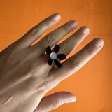 Anillo con base de acrílico transparente y dije de flor negra con centro plateado.
