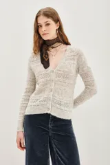 Cardigan de punto calado en color beige, con escote en V y cierre frontal de botones. Presenta un diseño de textura con franjas horizontales y mangas largas.