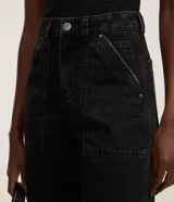 Pantalón de jeans estilo mom, tiro alto, color celeste claro lavado. Presenta bolsillos delanteros tipo carpinteiro con costuras marcadas y puños doblados en el bajo.