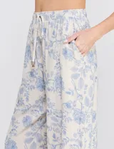 Pantalón palazzo de tiro alto con estampa floral azul sobre base beige, corte de pierna ancha, cintura elastizada con cordón de ajuste y bolsillos laterales.