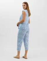 Pijama compuesto por remera sin mangas con escote redondo, botones frontales y detalle de puntilla, acompañado de un pantalón capri con cintura elástica. Presenta un estampado floral en tonos rosados sobre base gris.