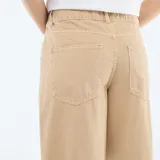 Pantalón de twill color beige con diseño de cintura asimétrica cruzada y corte recto de pierna ancha.
