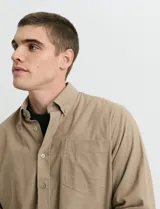Camisa de franela lisa con cuello button-down, manga larga, botones al tono y bolsillo frontal en el pecho.