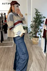 Sweater de punto corto con diseño a rayas horizontales en tonos beige, azul y bordó. Presenta cuello redondo y mangas largas con puños ajustados.