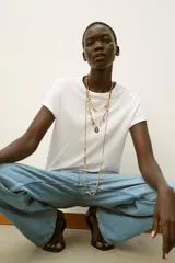 Pack de tres collares de diferentes largos, compuestos por cordones oscuros, piezas metálicas labradas, abalorios de colores, perlas y diversos charms colgantes con aplicaciones de cristales y brillos.