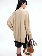 Sweater de tejido de punto color marrón, con cuello alto, corte amplio y tajos laterales en el ruedo. Presenta una costura vertical central en el frente y mangas largas con puños acanalados.