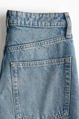 Pantalón de jean con diseño wide leg, de tiro alto y cinco bolsillos, en tono azul desgastado.