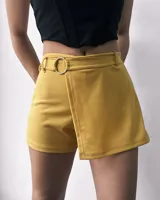 Short color mostaza con corte de pollera cruzada, cinturón con hebilla circular plateada y cierre lateral invisible.