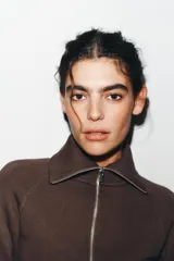 Chaqueta de felpa negra con cuello solapa, manga larga con puño, bolsillos de plastrón en el delantero y cierre frontal con cremallera.