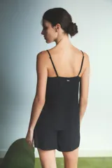 Conjunto de pijama compuesto por una musculosa con escote en V profundo decorado con encaje blanco y un short a juego. El diseño es de color negro, con breteles finos y corte holgado.