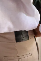 Pantalón de corte sastrero con pierna recta, confeccionado en gabardina y tencel. Presenta un diseño en color beige con detalle de rayas laterales en contraste.