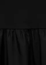 Vestido midi de color negro con diseño combinado. Presenta un cuerpo superior ajustado de tejido de punto con cuello redondo y mangas cortas, y una falda inferior amplia con vuelo confeccionada en algodón.