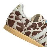 Championes Adidas modelo Japan con exterior de pelo sintético con estampado animal print tipo vaca en tonos marrón y blanco, tres tiras laterales y refuerzo en el talón de cuero blanco, cordones celestes y suela de goma color tostado.