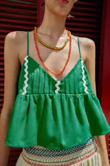 Top corto de lino color verde, con escote en pico, tirantes finos ajustables y detalle de ondas decorativas en color crema. Presenta un diseño con vuelo en la parte inferior y cierre en la espalda.