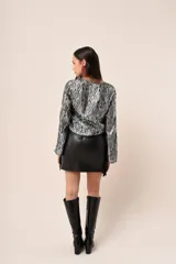 Blusa azul marino con estampado de hojas doradas, escote en V y mangas largas acampanadas.