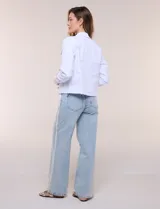 Campera de jean Baccini de color celeste claro, con cuello solapa, cierre frontal con botones metálicos, bolsillos en el pecho y ruedo con terminación desflecada.