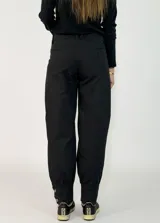 Pantalon de gabardina en color azul oscuro, de corte holgado con botamangas ajustadas mediante elástico.