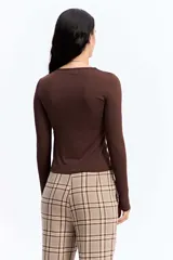 Remera de manga larga ajustada al cuerpo, confeccionada en tejido elástico de poliéster y spándex, con cuello redondo clásico.