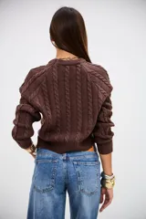 Sweater de punto color marrón chocolate, con diseño de trenzas verticales, cuello redondo y corte cropped.