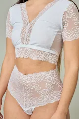 Conjunto de lencería blanco compuesto por un corpiño corto con mangas cortas y detalles de encaje floral en el escote y bajo busto, y una bombacha hipster tiro alto completamente de encaje.