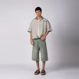 Camisa de manga corta de popelina con patrón a cuadros, calce boxy y largo a la cintura, con bolsillos y canesú cortados en diagonal.
