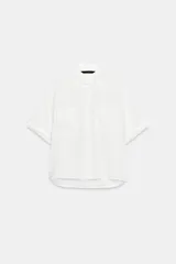Camisa de cuello solapa y manga corta con dobladillo, presenta bolsillos de plastrón en el frente, bajo asimétrico y cierre frontal con botones ocultos.