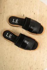 Sandalias planas de cuero marrón con tira ancha sobre el empeine. La plantilla es de cuero con la inscripción "LE".