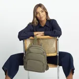 Mochila de tamaño mediano confeccionada en símil cuero color beige, con doble bolsillo frontal con cierre metálico, asa de mano superior y correas regulables de cinta tejida.