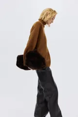 Buzo oversized de punto suave con cuello tortuga acanalado y abertura en la nuca. Presenta mangas raglán con costuras decorativas y terminaciones acanaladas en puños y bajo.