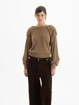 Sweater de punto color marrón, con cuello redondo, mangas largas con efecto globo y volados decorativos en los hombros. Presenta puños y cintura acanalados.
