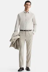 Camisa de vestir color beige claro, de manga larga, con cuello inglés y cierre de botones. Presenta un corte slim fit y bajo ligeramente redondeado.